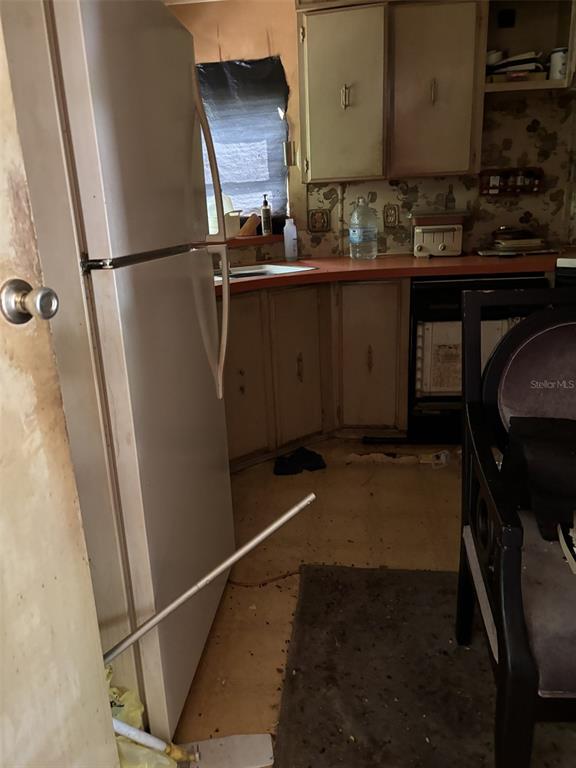 A kitchen features a white refrigerator, wooden cabinets, a red countertop, and patterned wallpaper — 12506 WALTON AVENUE, NEW PORT RICHEY, FL