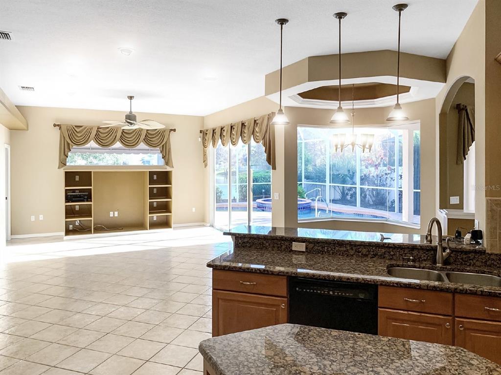 A kitchen with granite countertops overlooks a living area with tile floors and a pool — 14024 NIGHTHAWK TERRACE, LAKEWOOD RANCH, FL