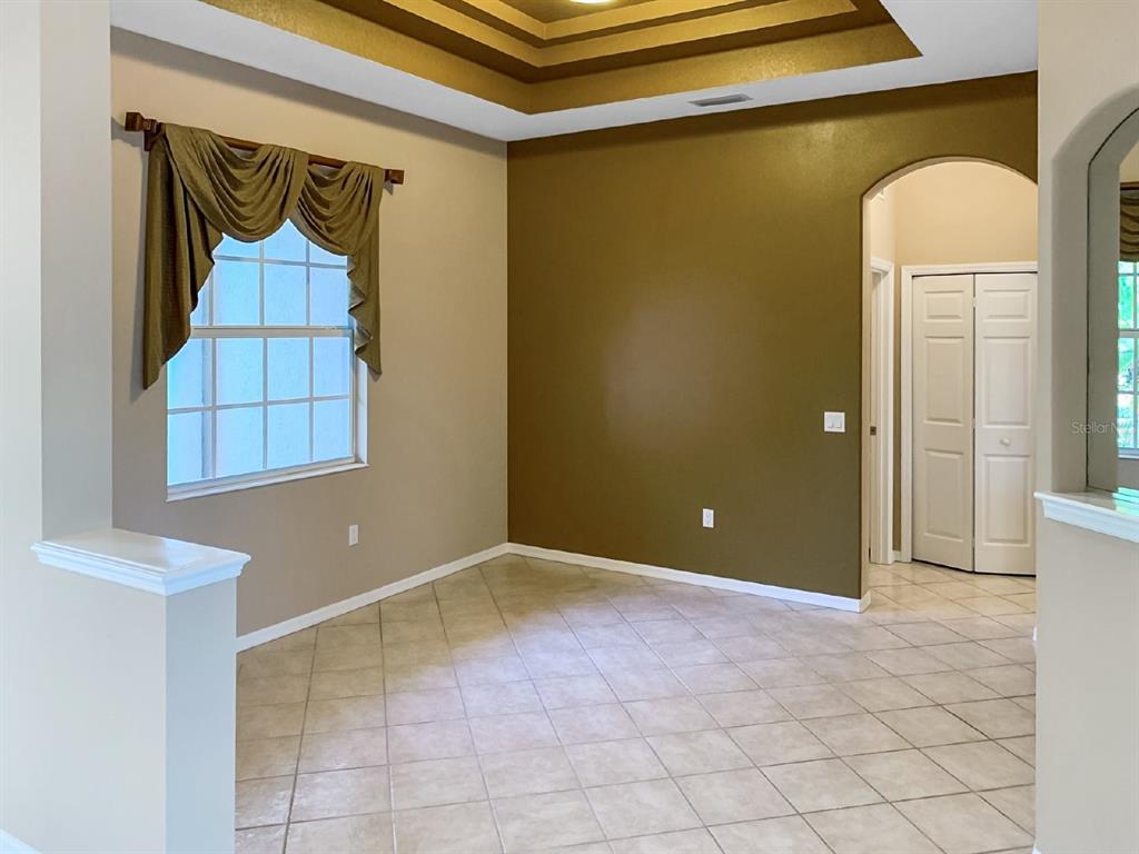 An empty room with a tray ceiling, tiled floor, and an arched doorway — 14024 NIGHTHAWK TERRACE, LAKEWOOD RANCH, FL