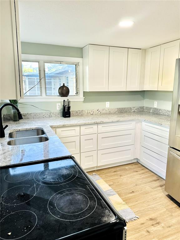 A kitchen features white shaker cabinets, granite countertops, and a black electric stove — 5654 12TH STREET, ZEPHYRHILLS, FL