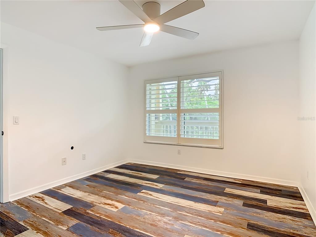 An empty bedroom features white walls, a ceiling fan, and multi-toned wood-look plank flooring — 1401 S PALMETTO AVENUE UNIT 616, DAYTONA BEACH, FL