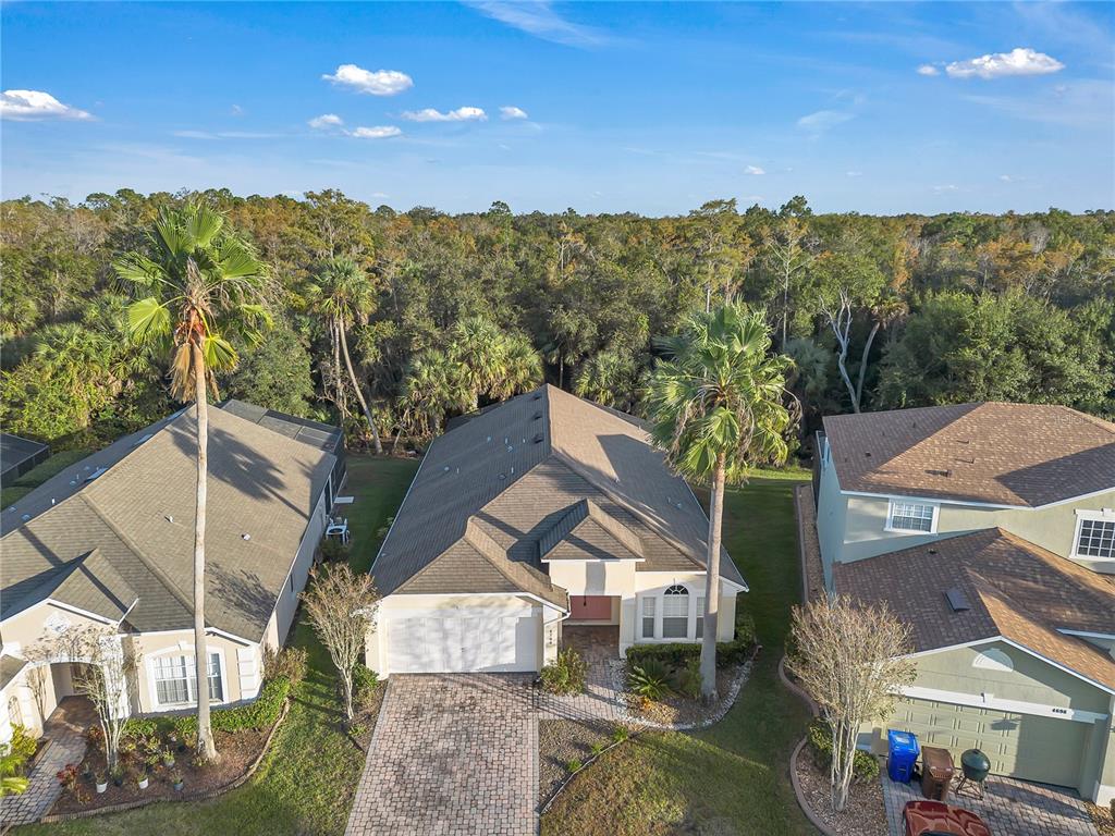 An aerial view shows a single-story house with a paved driveway and two palm trees — 4700 CUMBRIAN LAKES DRIVE, KISSIMMEE, FL