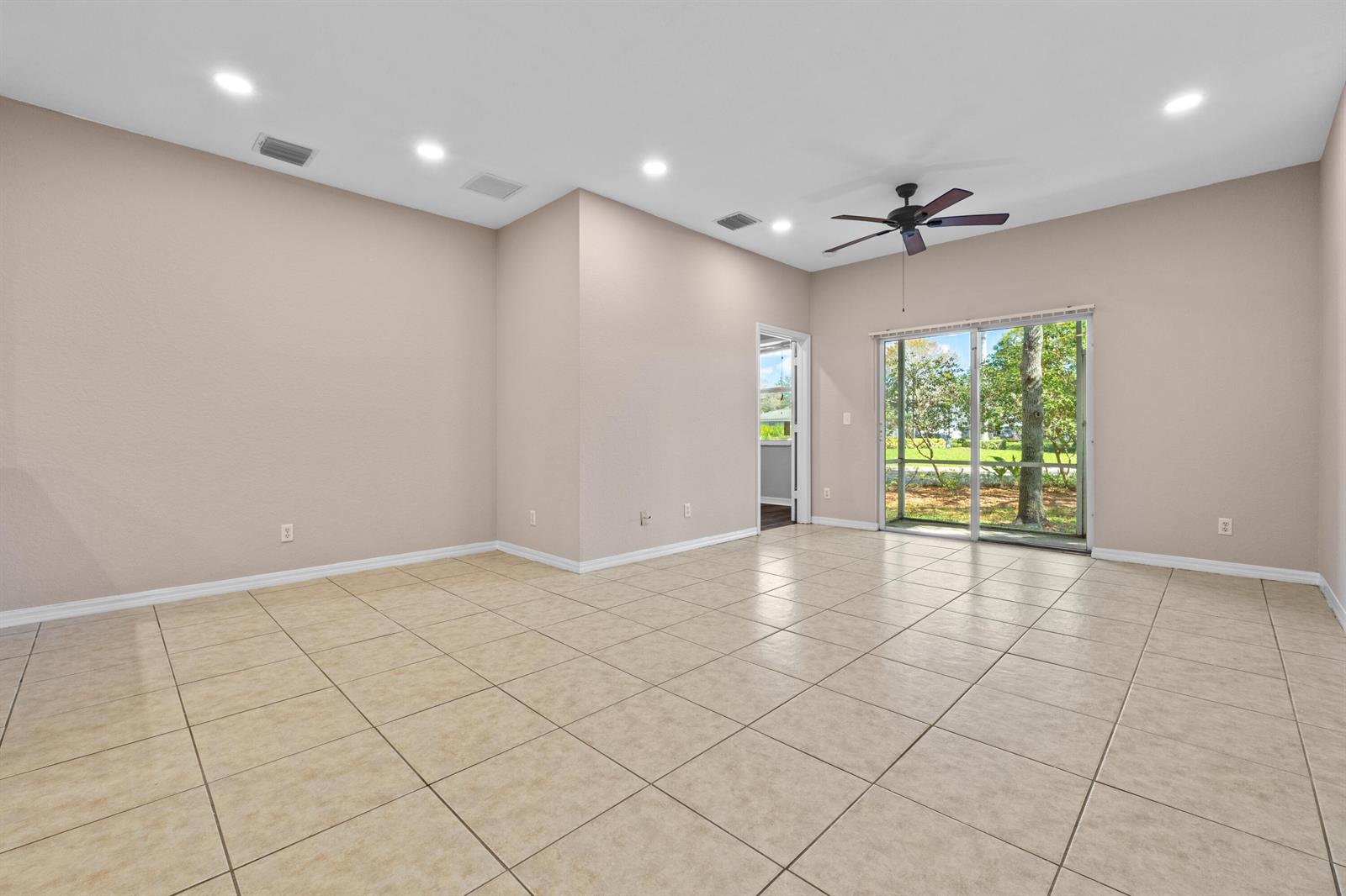 An empty room with beige tile flooring, recessed lighting, a ceiling fan, and sliding glass doors — 3105 Grandiflora Drive, FL 33467, FL