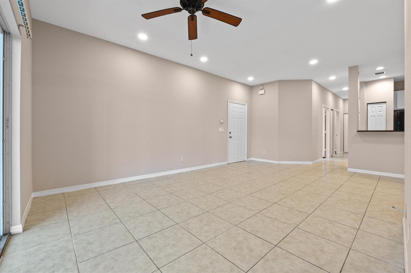 An empty living room features beige tile flooring, recessed lighting, and a ceiling fan — 3105 Grandiflora Drive, FL 33467, FL
