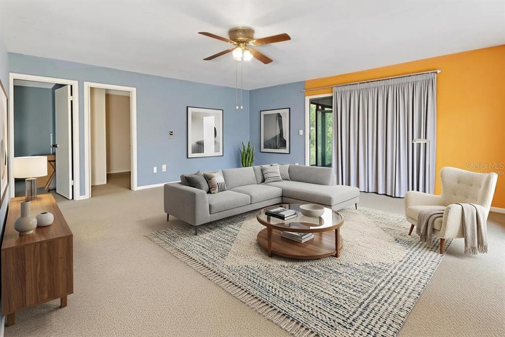 A living room features a gray sectional sofa, a round coffee table, and blue-orange walls — 25801 BLUE LAKES DRIVE, PAISLEY, FL