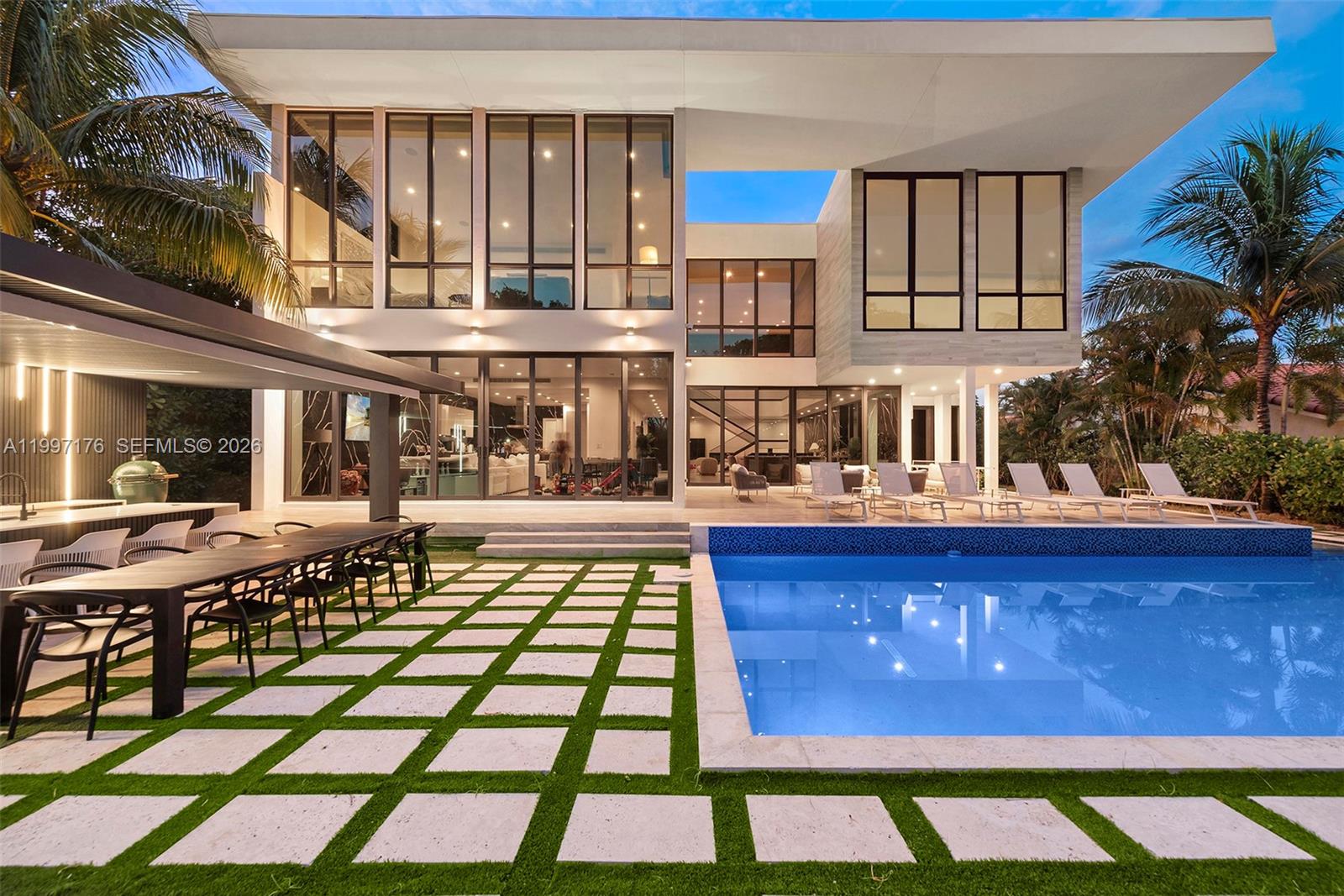 A modern two-story house features a swimming pool, outdoor dining area, and large glass windows — 521 Holiday Dr, Hallandale Beach FL 33009, HALLANDALE BEACH, FL