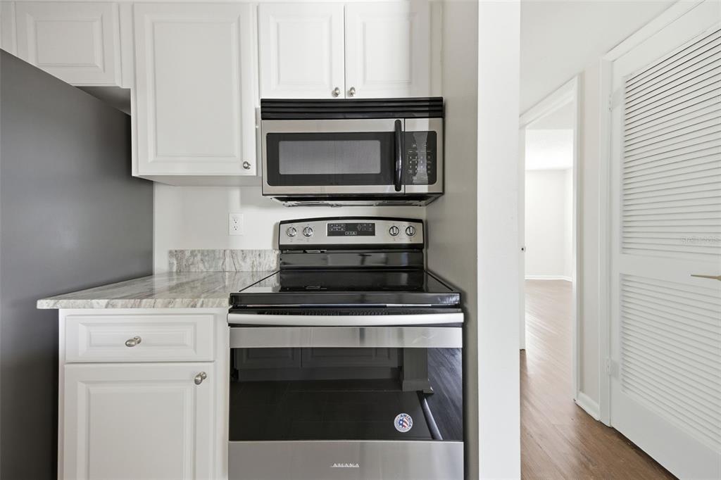 A kitchen features white cabinets, a stainless steel microwave, and an Amana electric range — 3102 W HORATIO STREET UNIT 12, TAMPA, FL
