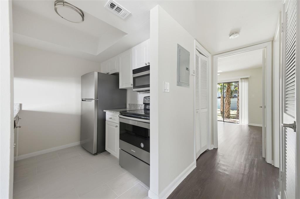 A galley-style kitchen with stainless steel appliances and white cabinets opens to a hallway — 3102 W HORATIO STREET UNIT 12, TAMPA, FL