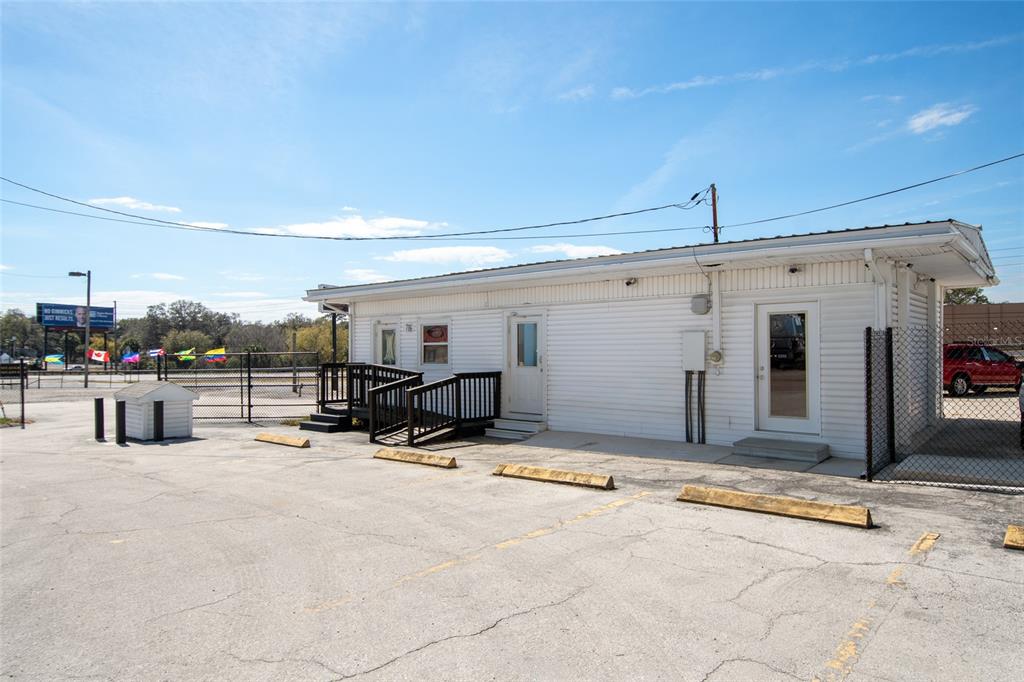A single-story white building with a ramp and parking lot under a blue sky — 7116 ROSE AVENUE, ORLANDO, FL