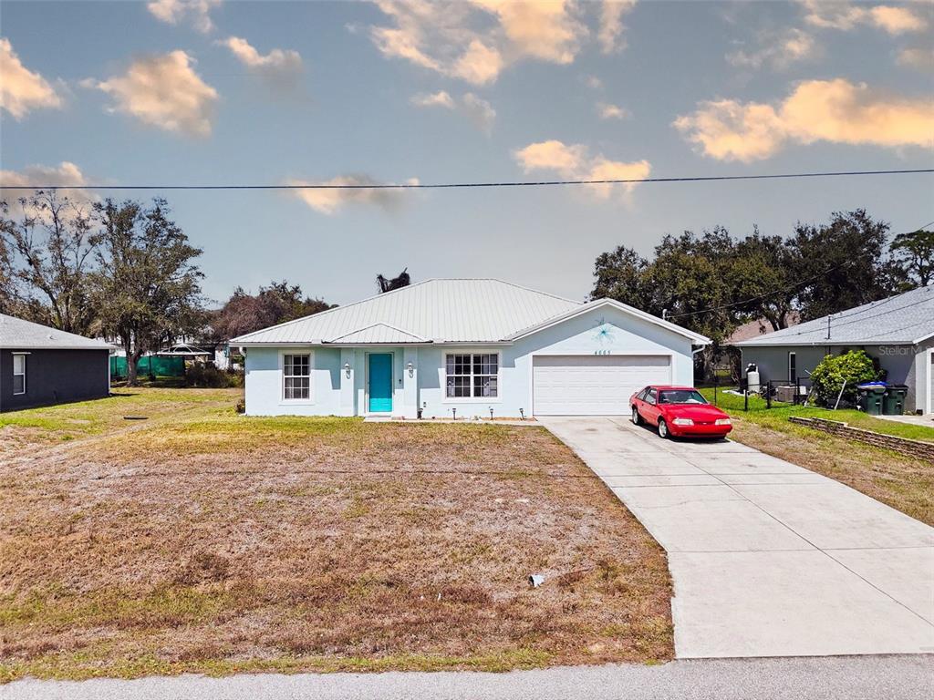 A light blue single-story house with a metal roof and a red car in the driveway — 4665 OAKLEY ROAD, NORTH PORT, FL