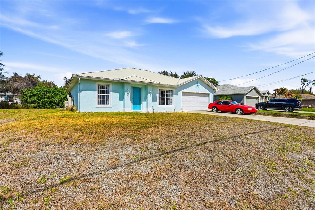 A light blue single-story house with a white garage and a large front lawn — 4665 OAKLEY ROAD, NORTH PORT, FL