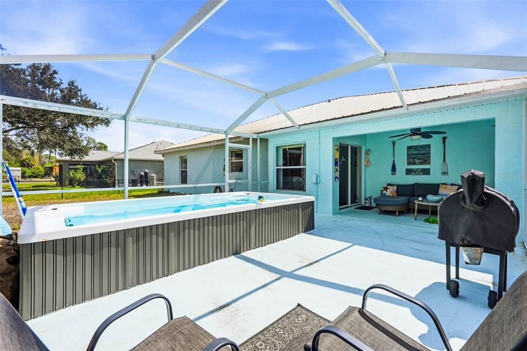 A backyard patio features a rectangular above-ground swim spa under a screened-in enclosure — 4665 OAKLEY ROAD, NORTH PORT, FL
