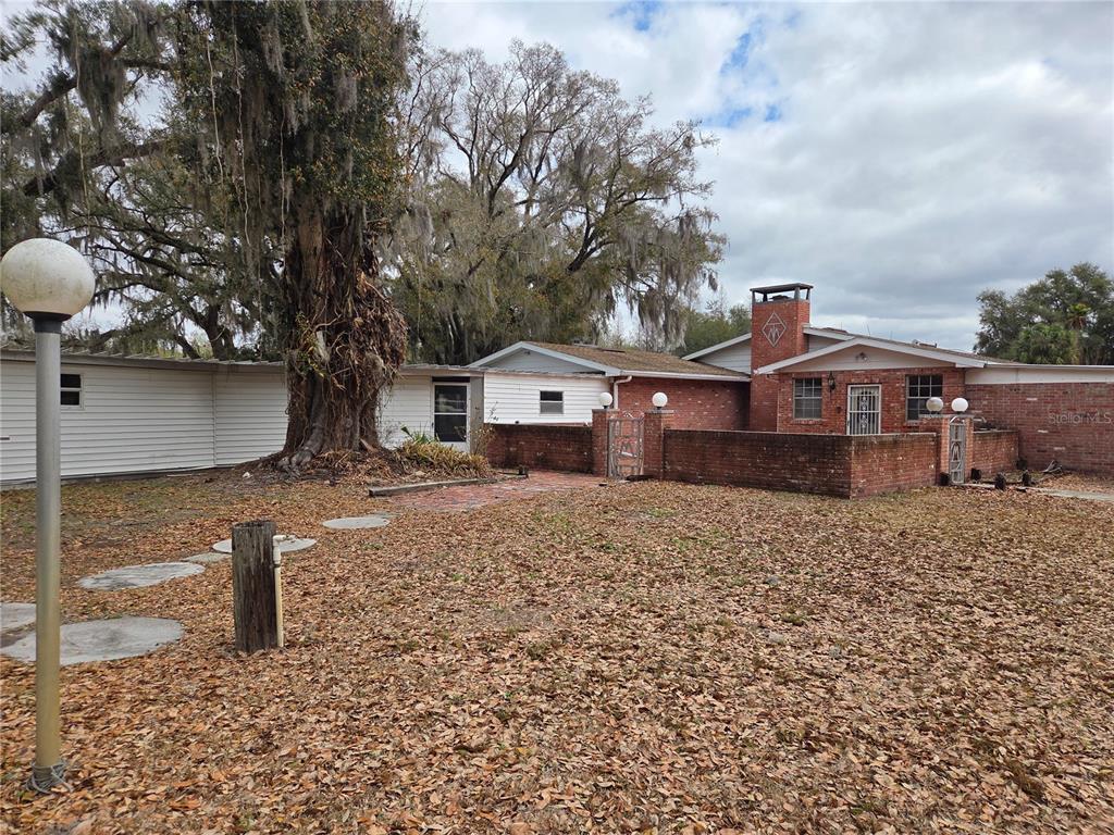 A single-story brick and siding house features a large tree and a brick courtyard — 4911 W SAM ALLEN ROAD, PLANT CITY, FL