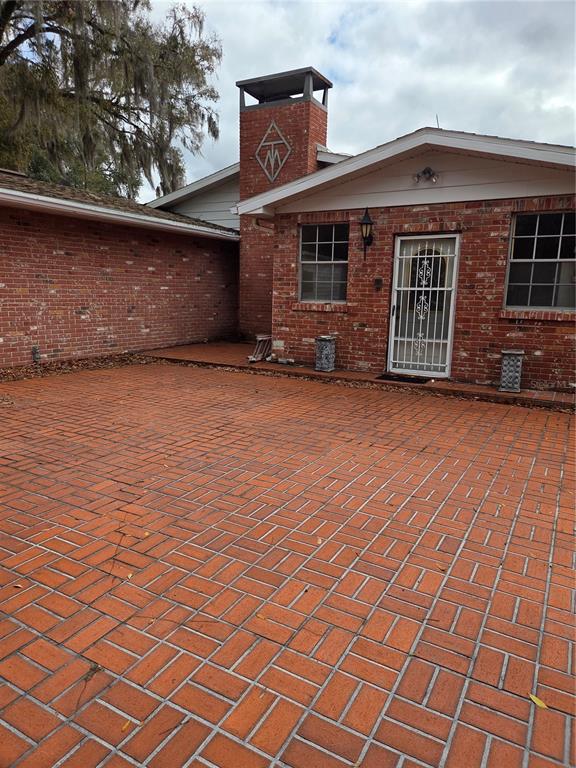 A brick patio leads to the entrance of a brick house with a chimney — 4911 W SAM ALLEN ROAD, PLANT CITY, FL