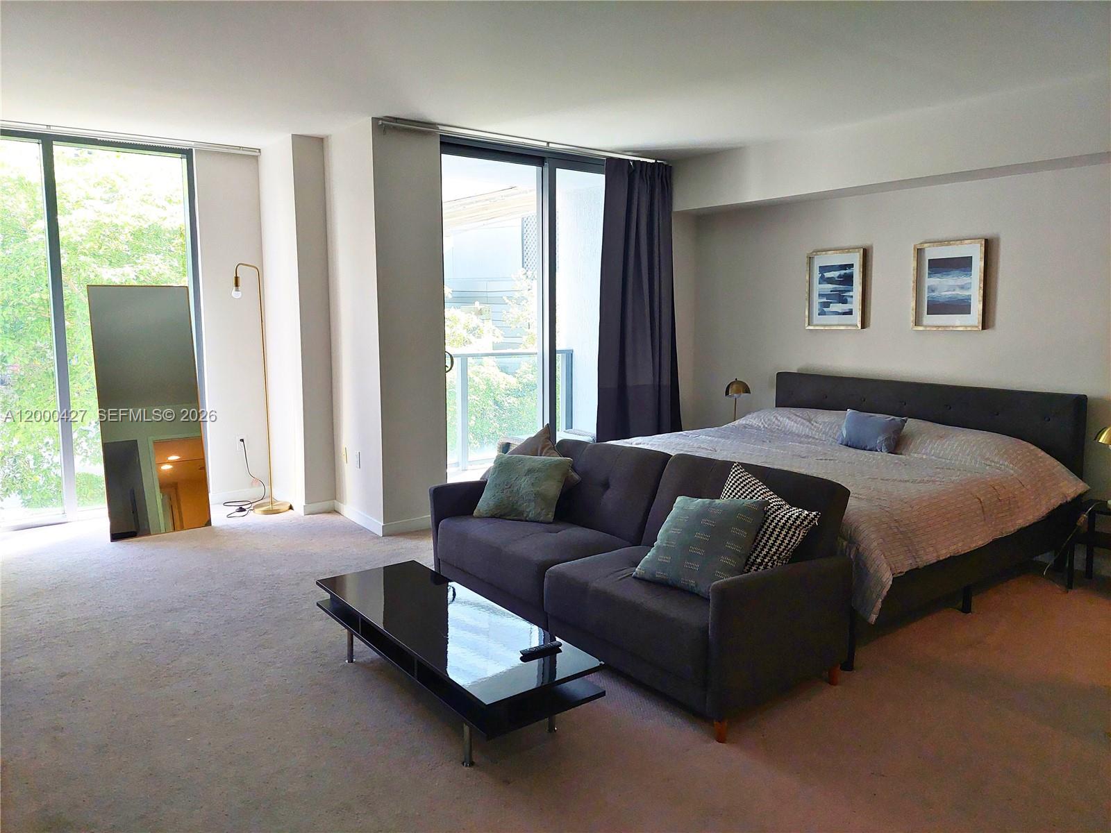 A bedroom features a bed, a sofa, a coffee table, and floor-to-ceiling windows — 31 SE 6th St # 403, Miami FL 33131, MIAMI, FL