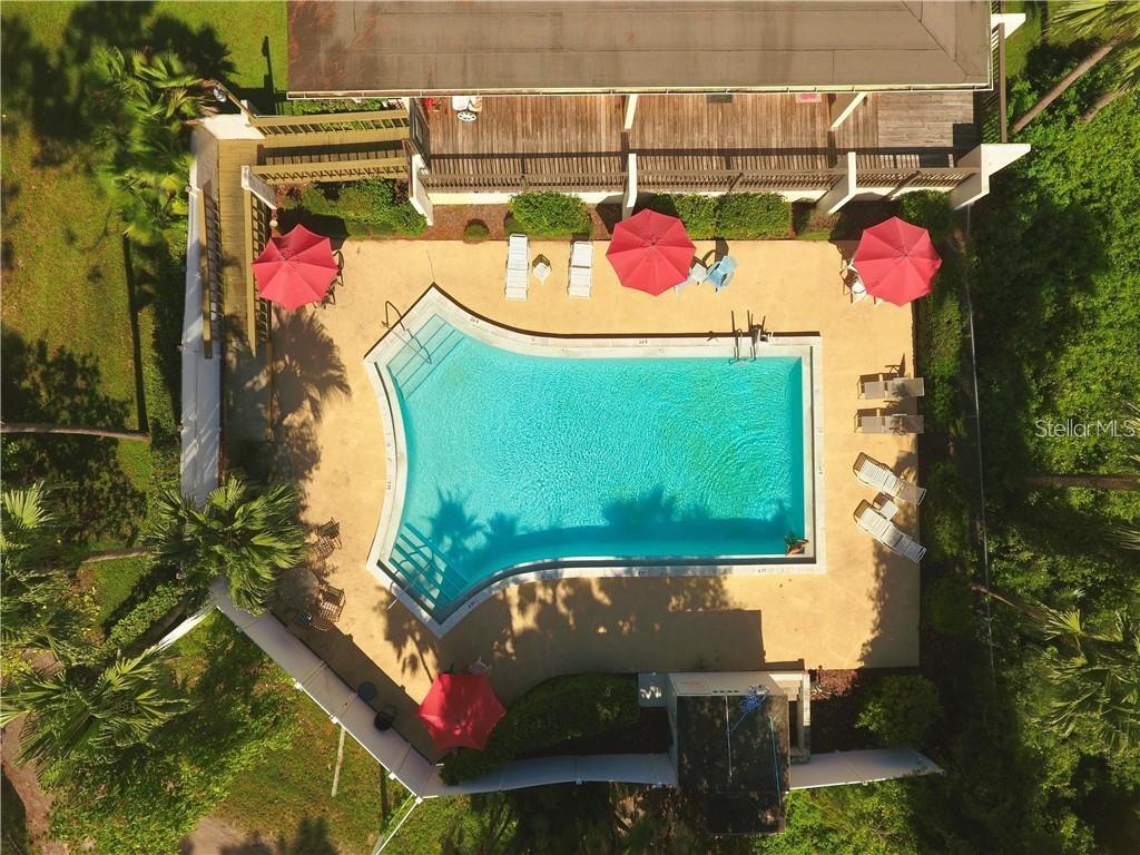 An aerial view shows a swimming pool with red umbrellas and lounge chairs on a deck — 400 EL CAMINO DRIVE UNIT 210, WINTER HAVEN, FL