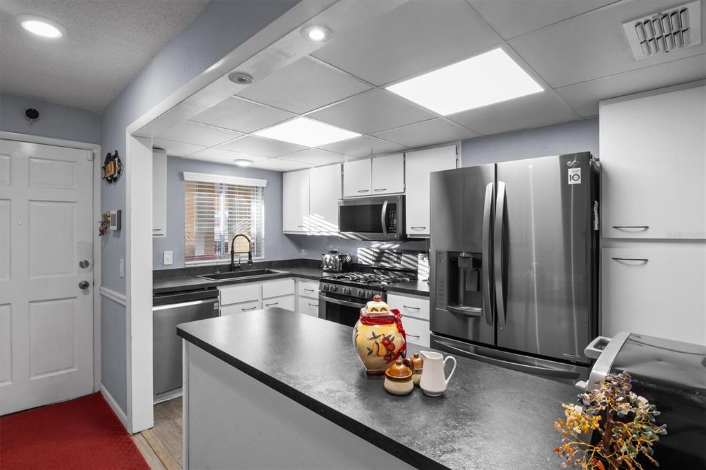 A kitchen features a breakfast bar, stainless steel appliances, white cabinets, and dark countertops — 400 EL CAMINO DRIVE UNIT 210, WINTER HAVEN, FL