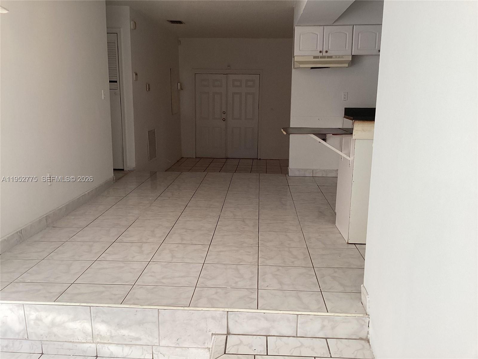 A tiled living area leads to a kitchen with white cabinets and a breakfast bar — 4824 NW 15th Ct, Miami FL 33142, MIAMI, FL