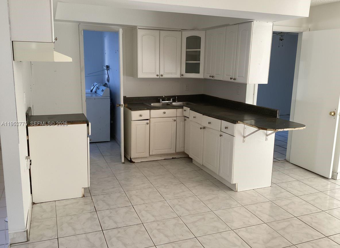 A kitchen features white cabinets, dark countertops, and light-colored tile flooring — 4824 NW 15th Ct, Miami FL 33142, MIAMI, FL