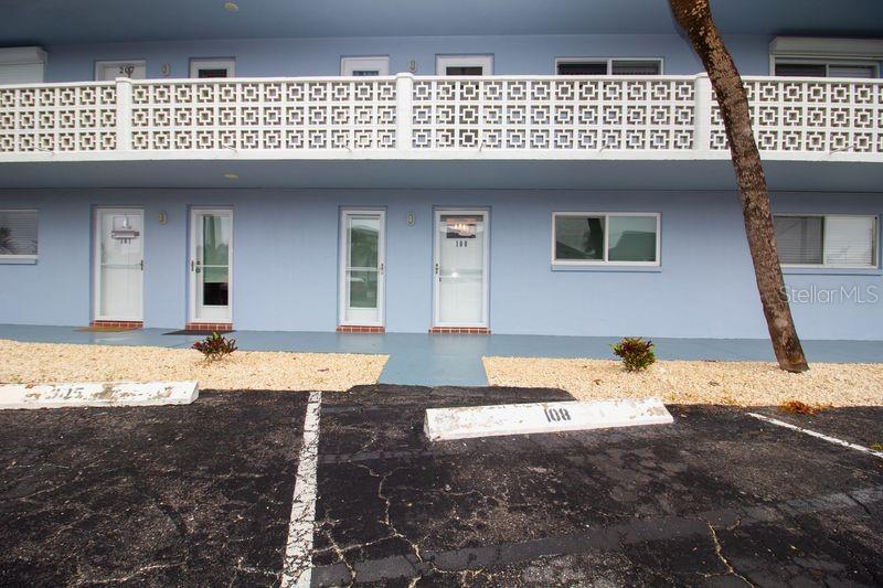 The exterior of a two-story blue apartment building with a white decorative balcony railing — 280 126TH AVENUE UNIT 108, TREASURE ISLAND, FL