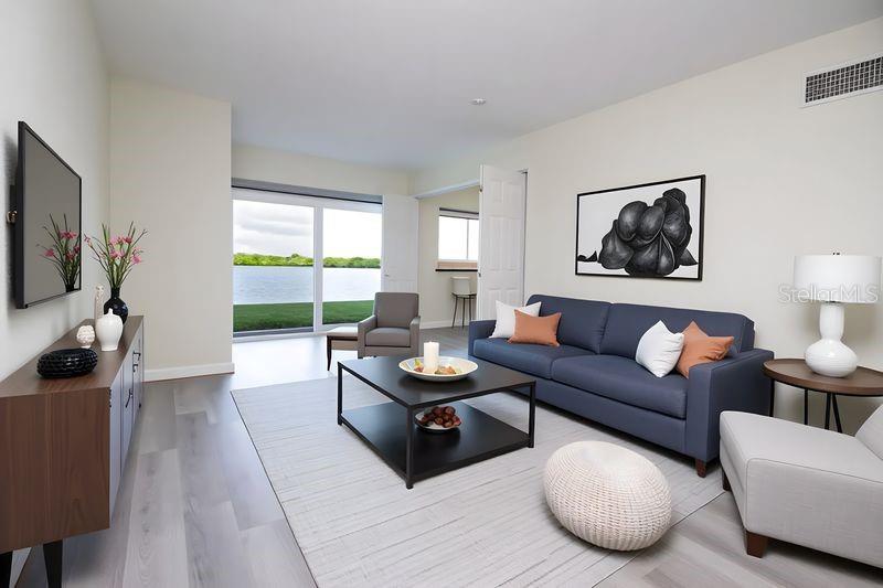 A living room features a blue sofa, a coffee table, and a view of water — 280 126TH AVENUE UNIT 108, TREASURE ISLAND, FL