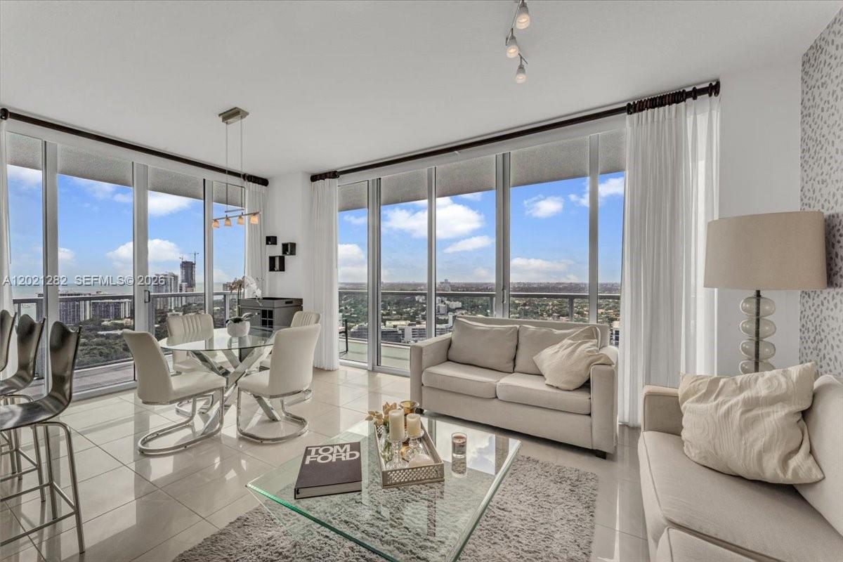 A bright living and dining area features floor-to-ceiling windows, tile flooring, and modern furniture — 79 SW 12th St, Miami FL 33130, MIAMI, FL