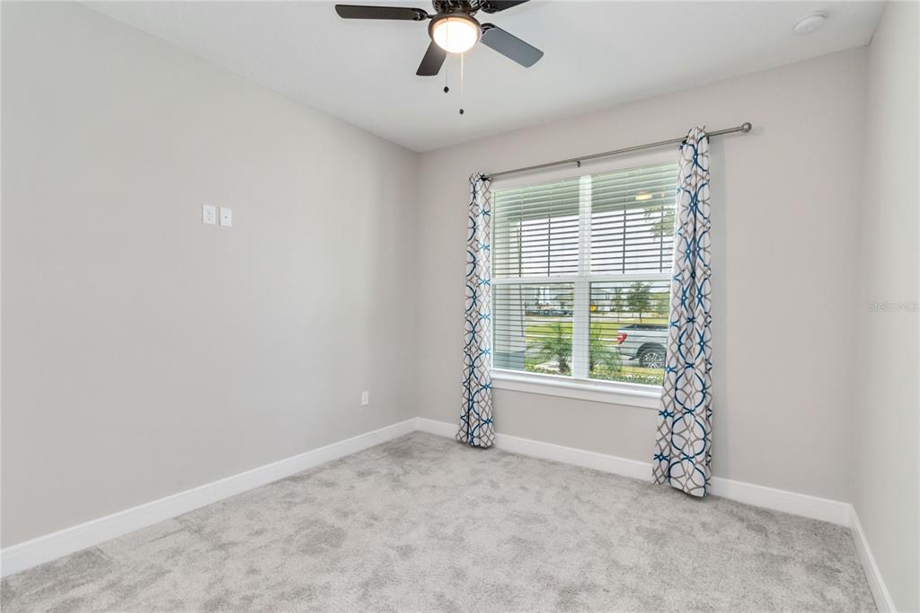 A bedroom with gray carpet, light walls, a ceiling fan, and a window with curtains — 4067 MEANDERING BAY DRIVE, APOPKA, FL