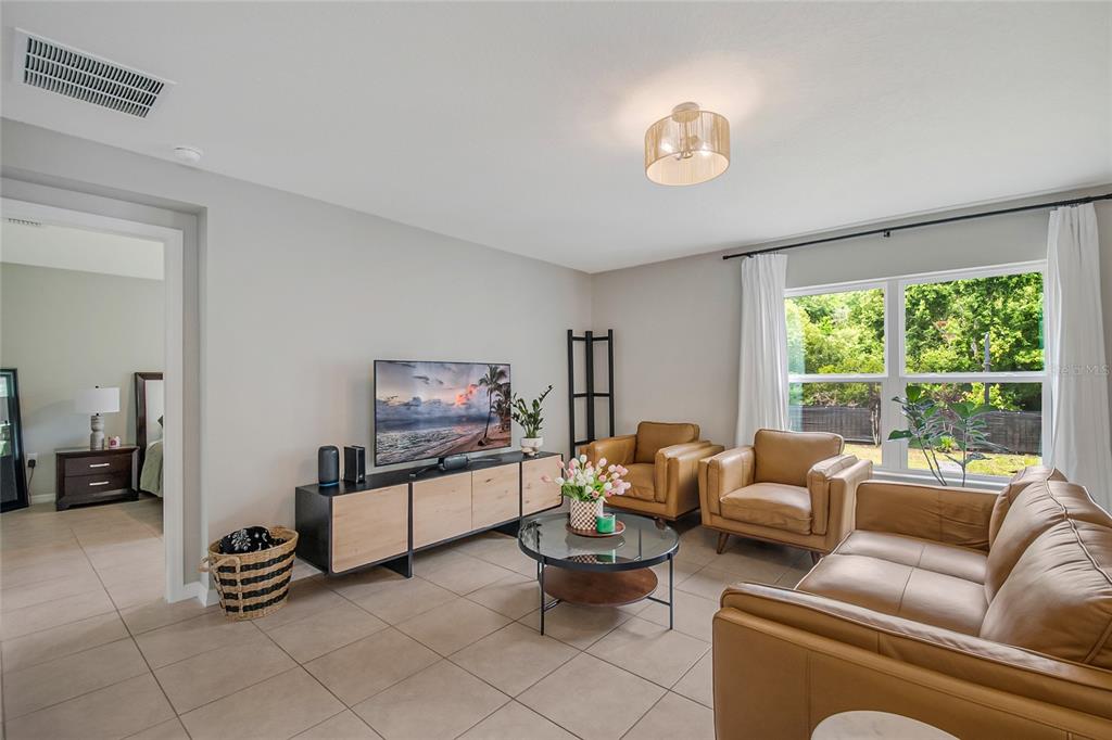 A living room features tan leather furniture, a glass coffee table, and a media console — 2865 MOSSHIRE CIRCLE, ST CLOUD, FL