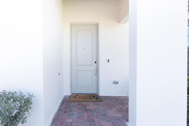 A light-colored front door with a doormat sits under a covered entryway with brick pavers — 3509 Bauer Road, Royal Palm Beach FL 33411, ROYAL PALM BEACH, FL