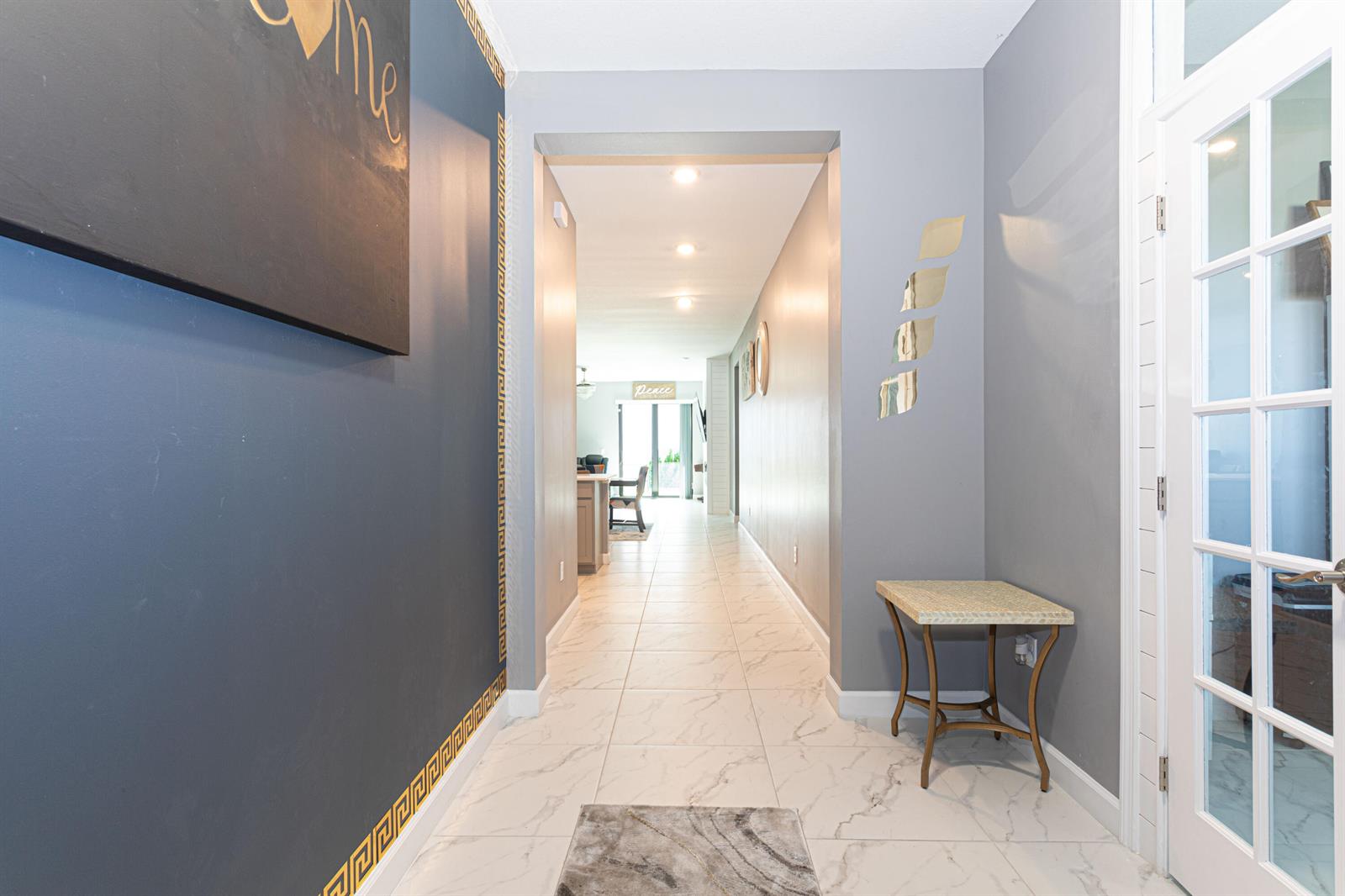 A hallway with marble-look tile floors leads toward a bright open living area — 3509 Bauer Road, Royal Palm Beach FL 33411, ROYAL PALM BEACH, FL