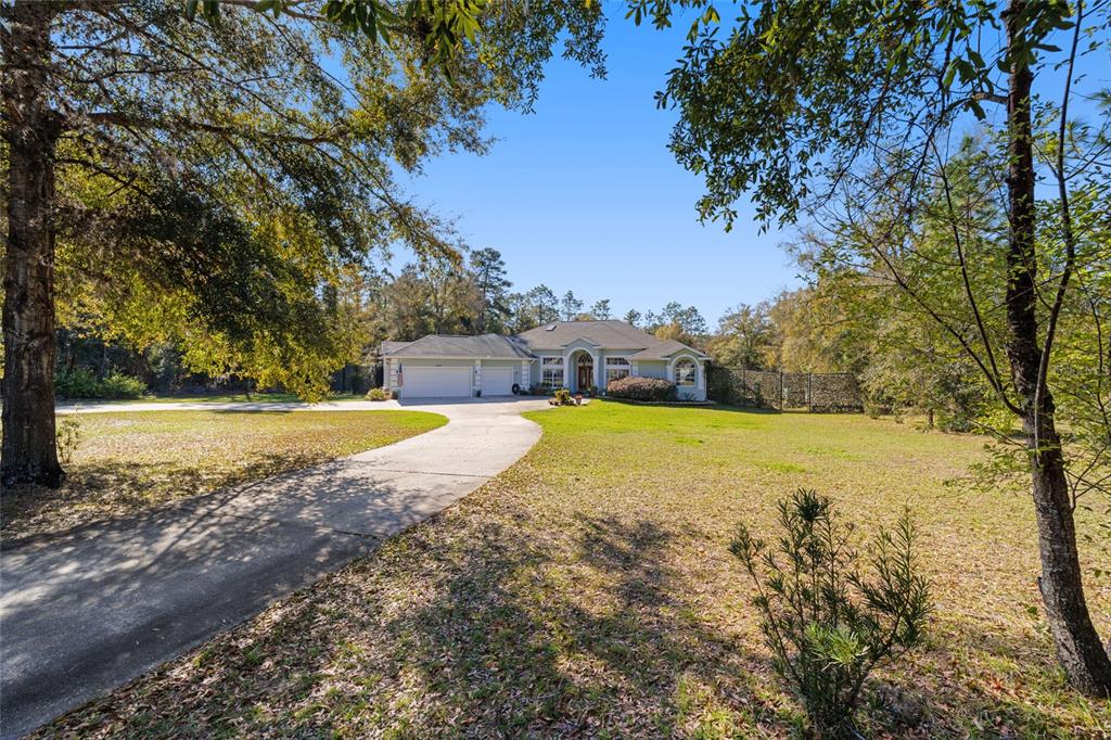 A single-story house with a two-car garage and a long driveway sits on a lawn — 12880 SW 66TH STREET, OCALA, FL