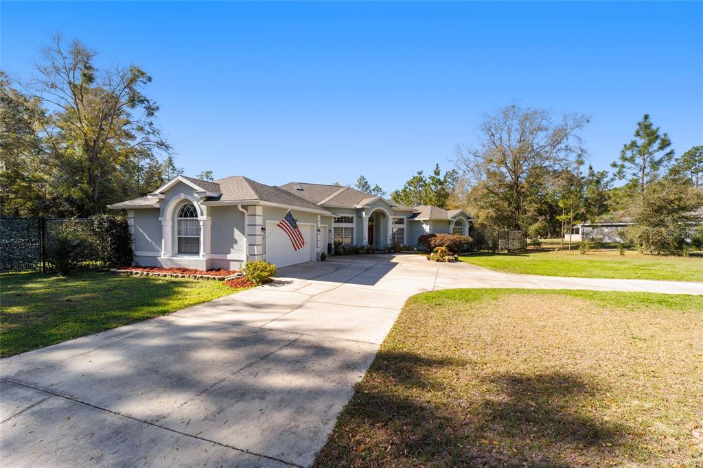 A single-story house with a concrete driveway, a two-car garage, and an American flag — 12880 SW 66TH STREET, OCALA, FL