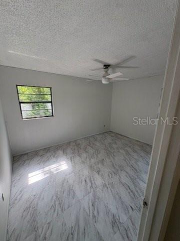 A bedroom with white walls, a ceiling fan, and light-colored marble-patterned tile flooring — 2558 N COUNTY RD #470, LAKE PANASOFFKEE, FL