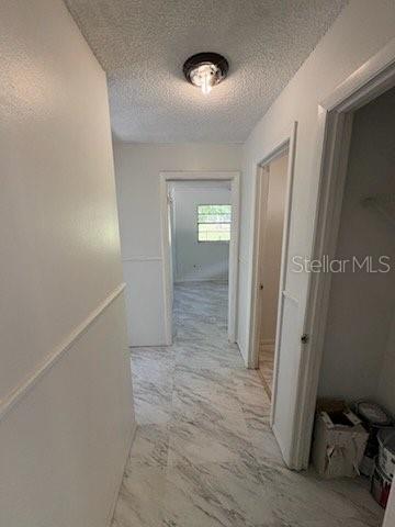 A hallway with white walls, marble-patterned tile flooring, and a ceiling-mounted light fixture — 2558 N COUNTY RD #470, LAKE PANASOFFKEE, FL