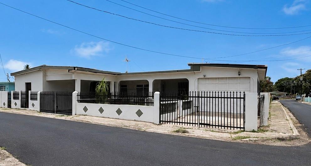 A single-story white house with a black metal fence and a garage — 11 SINGAPUR, JUANA DIAZ, PR