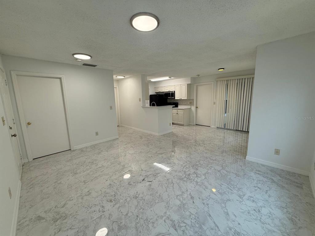 An open-concept living and dining area features white marble-look tile flooring and a kitchen — 1089 S HIAWASSEE ROAD UNIT 314, ORLANDO, FL
