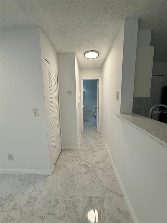 A hallway with marble-look tile flooring leads to a bathroom with a white door — 1089 S HIAWASSEE ROAD UNIT 314, ORLANDO, FL