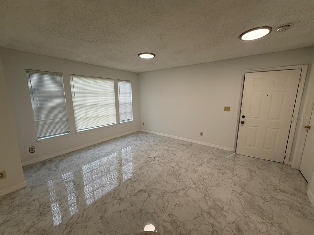 An empty room features white marble-look tile flooring, light gray walls, and three windows — 1089 S HIAWASSEE ROAD UNIT 314, ORLANDO, FL
