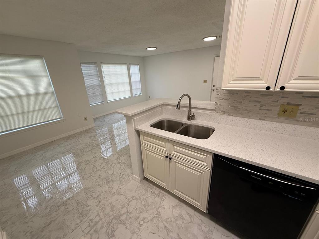 A kitchen with white cabinets, a double sink, and a black dishwasher overlooks a room — 1089 S HIAWASSEE ROAD UNIT 314, ORLANDO, FL