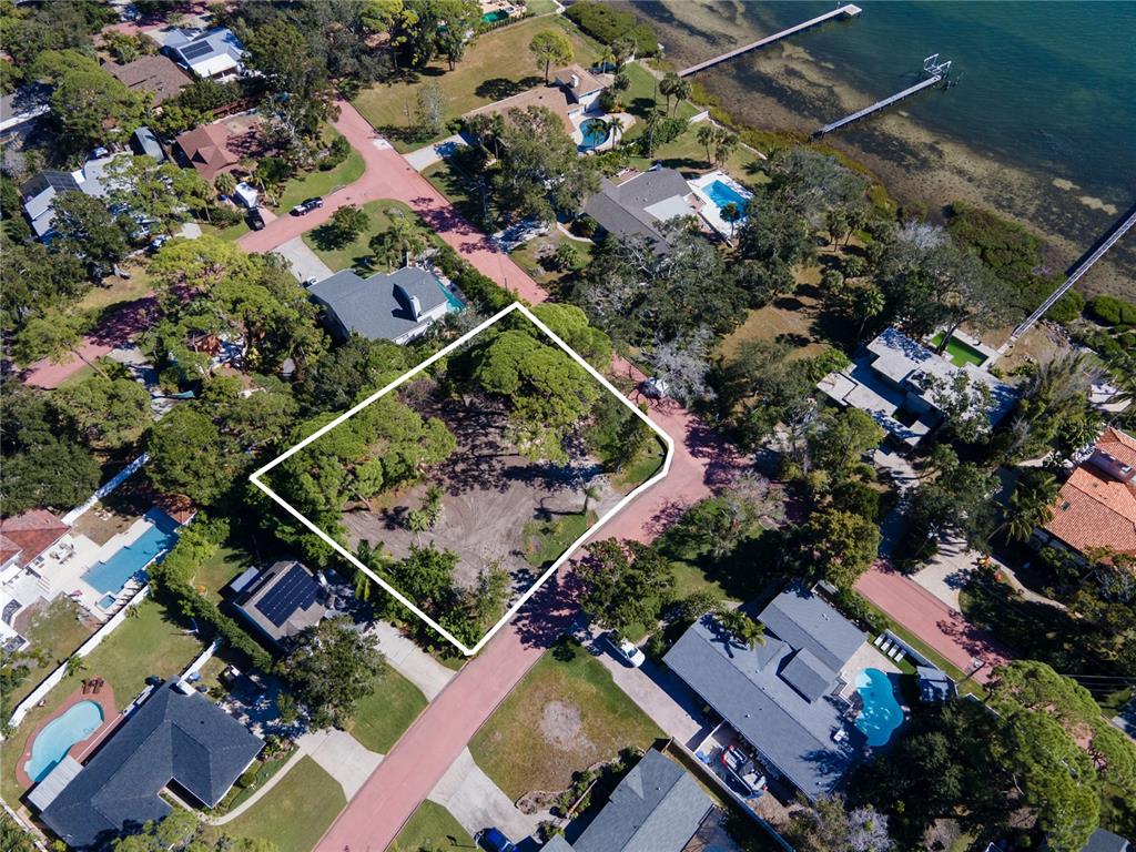 An aerial view shows a vacant, wooded residential lot outlined in white within a neighborhood — 1125L FRIENDLY WAY S, ST PETERSBURG, FL
