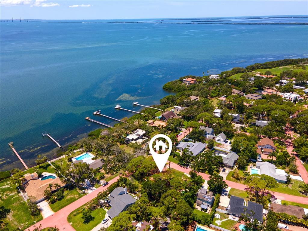 An aerial view shows a waterfront neighborhood with houses, docks, and a marked property location — 1125L FRIENDLY WAY S, ST PETERSBURG, FL