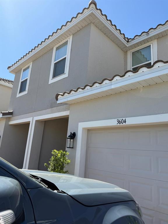 A two-story stucco house exterior features a garage, a tiled roof, and two upper-level windows — 3604 LANDING NET DRIVE, KISSIMMEE, FL