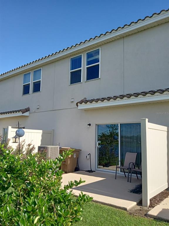 A two-story townhouse exterior features a concrete patio, sliding glass doors, and privacy fencing — 3604 LANDING NET DRIVE, KISSIMMEE, FL