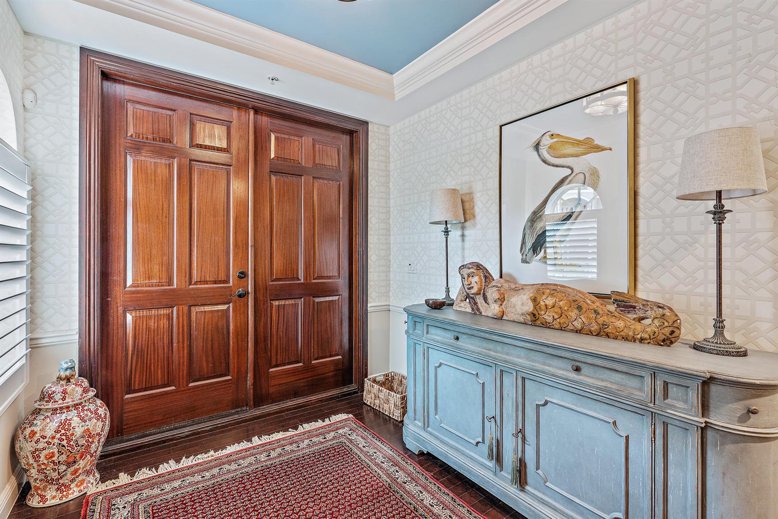 An entryway features a wooden double door, a blue sideboard, a pelican print, and wallpaper — 126 Tierra Lane # 4, Jupiter FL 33477, JUPITER, FL