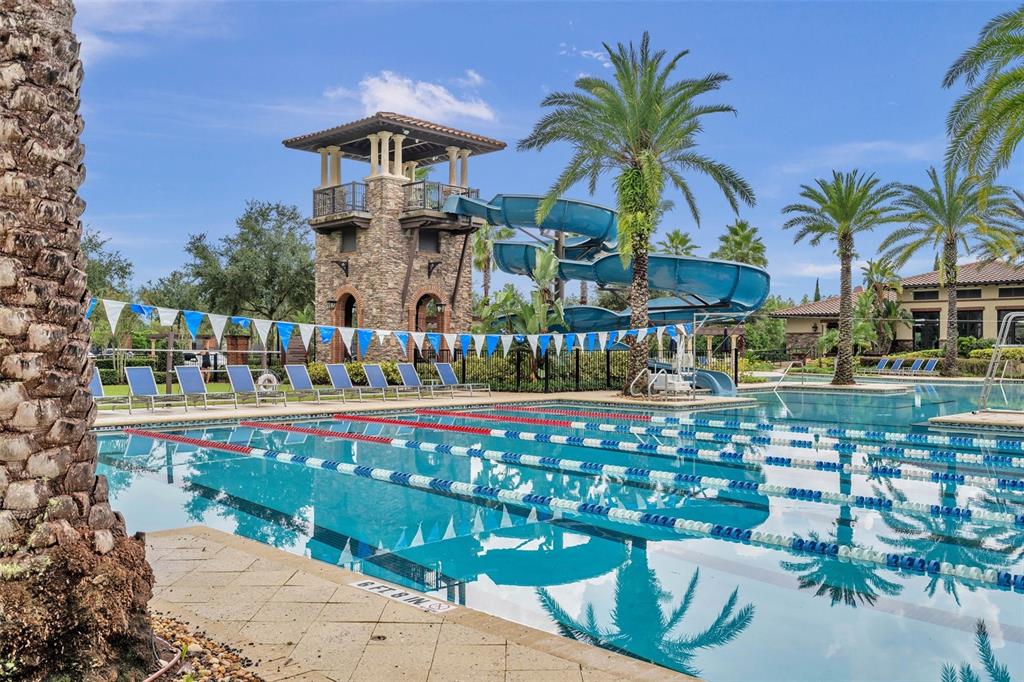 A swimming pool with lap lanes, a water slide, and a stone tower in a courtyard — 29657 PICANA LANE, WESLEY CHAPEL, FL