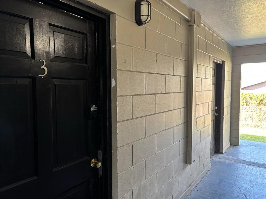 A black door marked with the number three sits beside a beige concrete block wall — 310 FARNOL STREET SW UNIT 3, WINTER HAVEN, FL