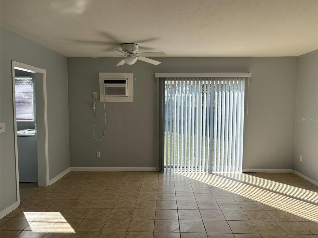A living room features light gray walls, tile flooring, a ceiling fan, and sliding doors — 310 FARNOL STREET SW UNIT 3, WINTER HAVEN, FL