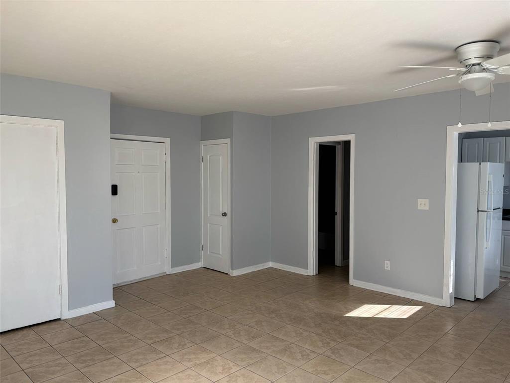 A room with light gray walls, tile flooring, a white front door, and a ceiling fan — 310 FARNOL STREET SW UNIT 3, WINTER HAVEN, FL