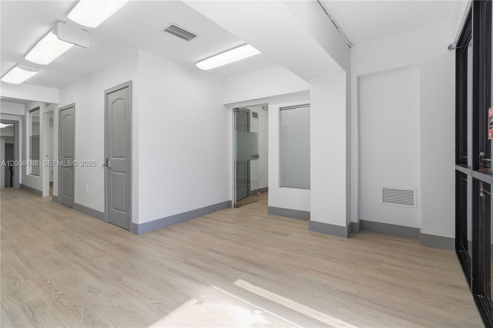 An office hallway features light wood flooring, white walls, gray trim, and multiple doorways — 470 NW 22nd Ave, Miami FL 33125, MIAMI, FL