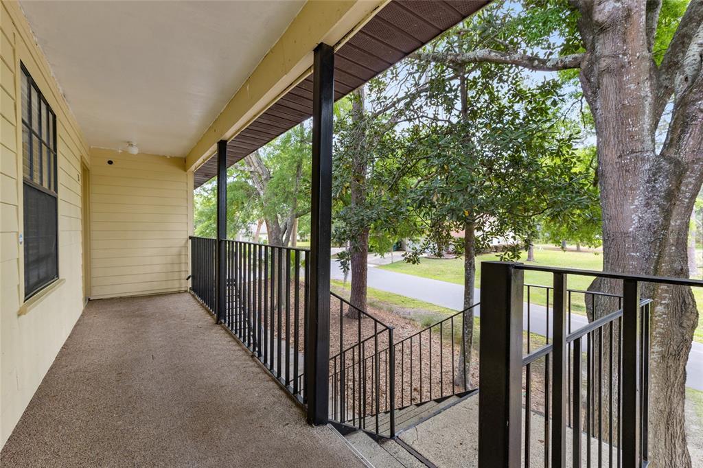 An outdoor balcony with a concrete floor, black metal railings, and stairs leading to ground level — 6400 NW 106TH PLACE UNIT 20, ALACHUA, FL